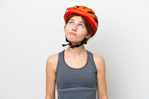 Young cyclist English woman isolated on white background and looking up