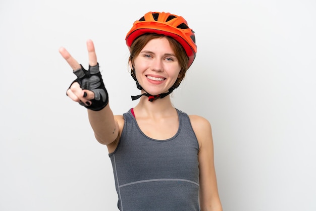 Photo young cyclist english woman isolated on white background smiling and showing victory sign