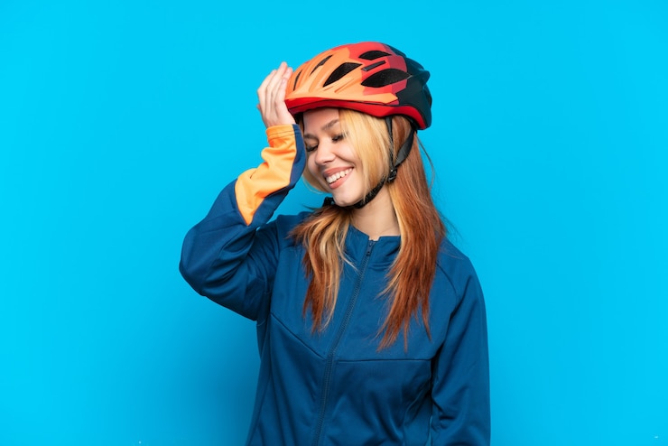 Photo young cyclist girl isolated on blue background has realized something and intending the solution