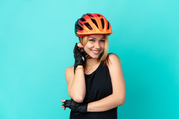 Young cyclist girl over isolated blue background laughing