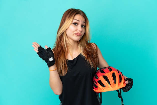 Young cyclist girl over isolated blue background making doubts gesture