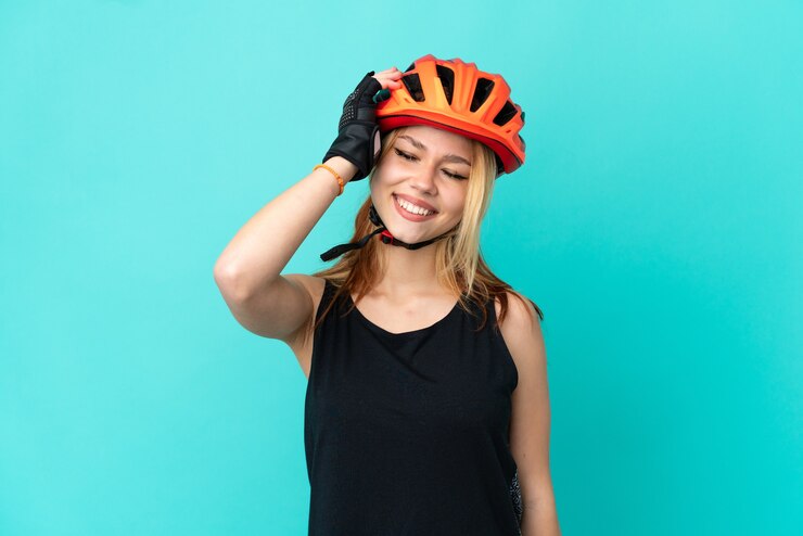 Photo young cyclist girl over isolated blue background smiling a lot