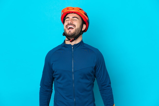 Молодой велосипедист человек, изолированные на синем фоне смеясь
