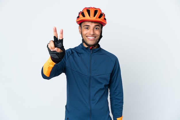 Young cyclist man isolated smiling and showing victory sign