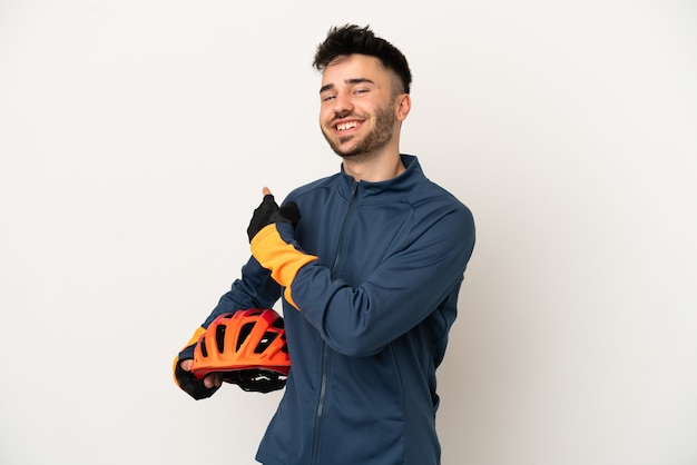 Young cyclist man isolated on white background pointing back