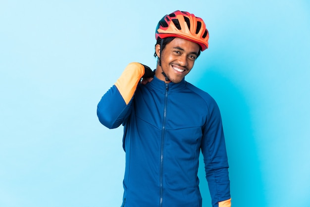 Young cyclist man with braids over isolated background laughing