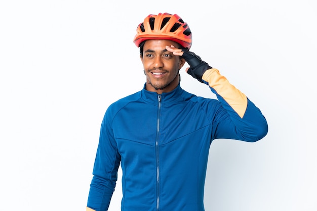 Young cyclist man with braids over saluting with hand with happy expression