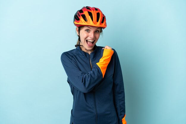 Young cyclist woman isolated on blue background celebrating a victory