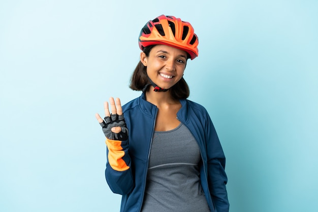 Young cyclist woman isolated on blue background happy and counting four with fingers