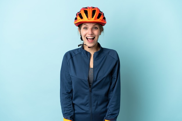 Young cyclist woman isolated on blue background with surprise facial expression