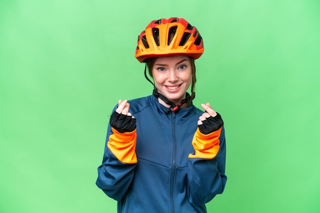 Young cyclist woman over isolated chroma key background making money gesture