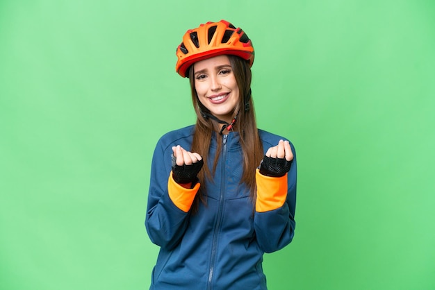 Young cyclist woman over isolated chroma key background making money gesture