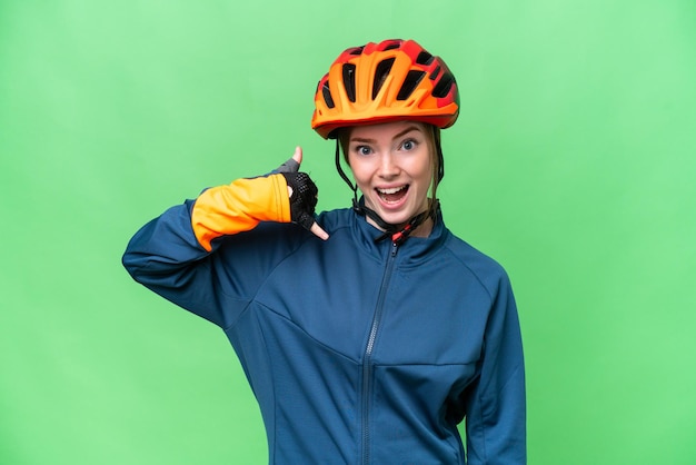 Giovane donna ciclista su sfondo chroma key isolato che fa il gesto del telefono call me back sign