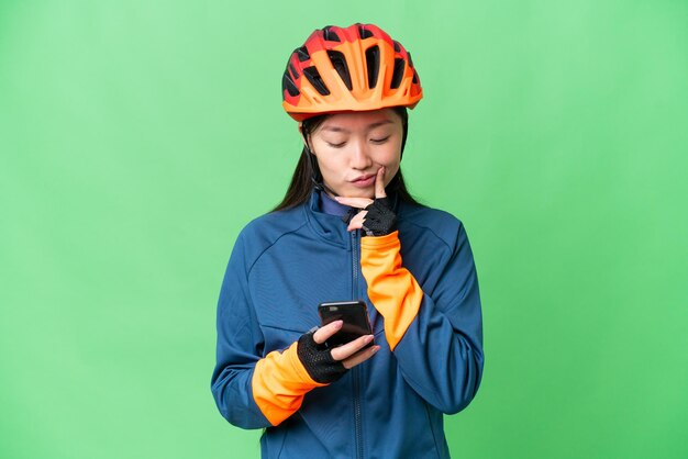 孤立したクロマキーの背景を考え、メッセージを送る若いサイクリストの女性