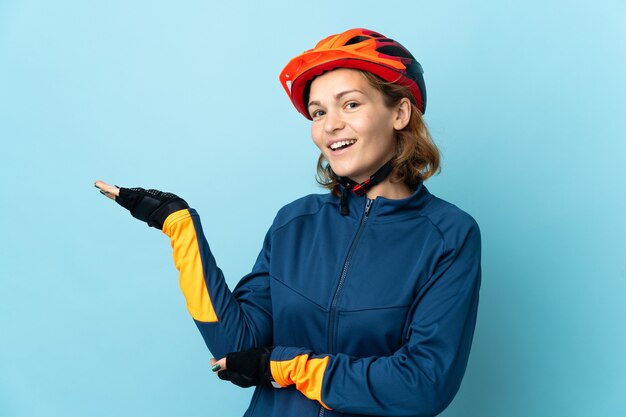 Young cyclist woman isolated extending hands to the side for inviting to come