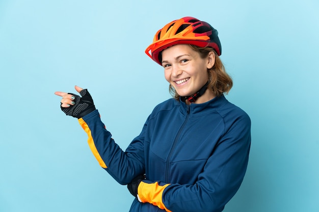 Young cyclist woman isolated pointing finger to the side