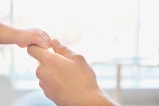 Young dad holding hand of his little son closeup