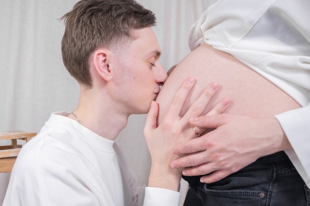 Young dad kissing pregnant belly .