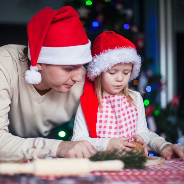 산타 모자에 작은 딸과 함께 젊은 아빠 크리스마스 진저 쿠키를 구워