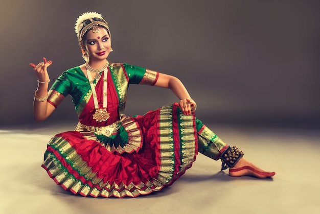 Young dancer of classical Indian dance dressed in traditional suit is demonstrating one of the pose