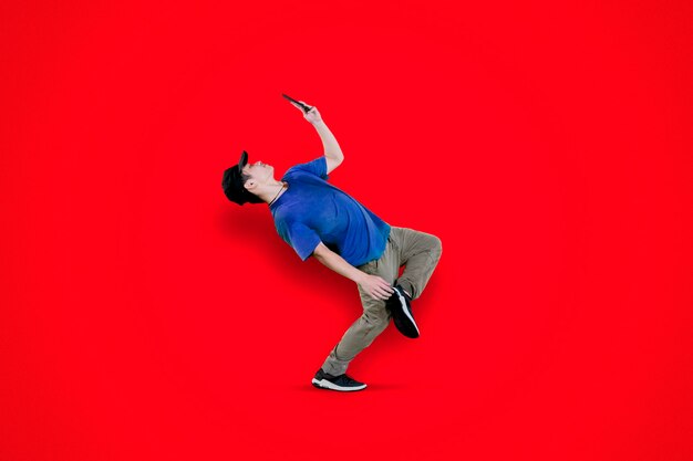 Young dancer doing break dance with his smartphone