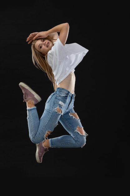 Young dancer jumps up hands held above her head Side to side with the camera Long blonde hair