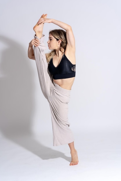 Young dancer in studio photo session with a white background ballet in an exercise lifting the leg