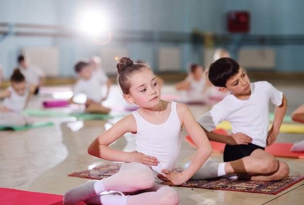 Young dancers in the ballet studio. Young dancers perform gymnastic exercises during a warm-up in the classroom. Sport, gymnastics, child development