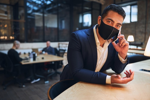 Giovane uomo d'affari dai capelli scuri che comunica sullo smartphone