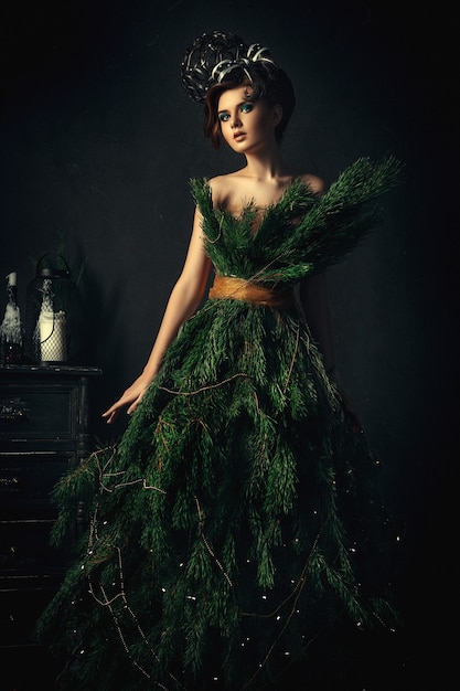 Молодая темноволосая модель позирует в креативном платье из ели