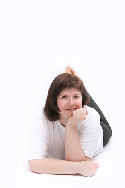 Young dark-haired woman lies on stomach with her hand prop up head isolation on white background. Happy young woman.