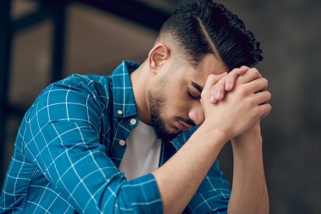 Young darkhaired man sitting with an unhappy look