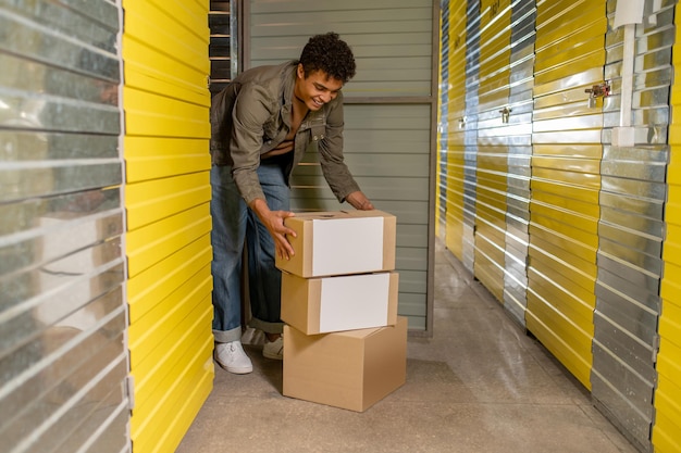 Photo young darkhaired man with boxes in the stockhouse