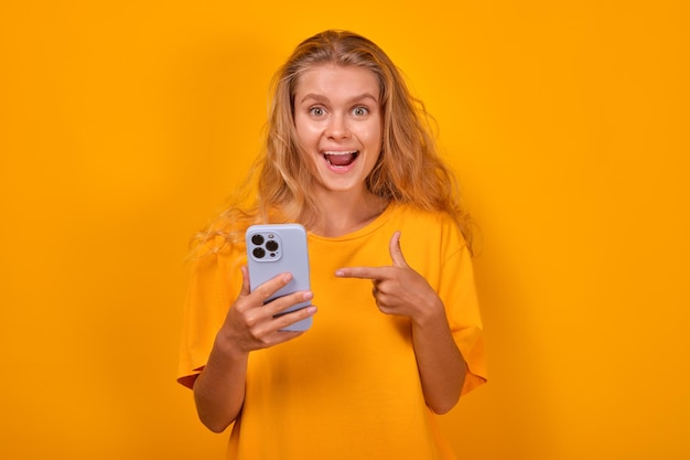 Young delighted beautiful caucasian woman with phone in hands screams loudly