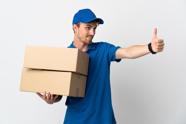 Young delivery blonde man isolated on white wall giving a thumbs up gesture