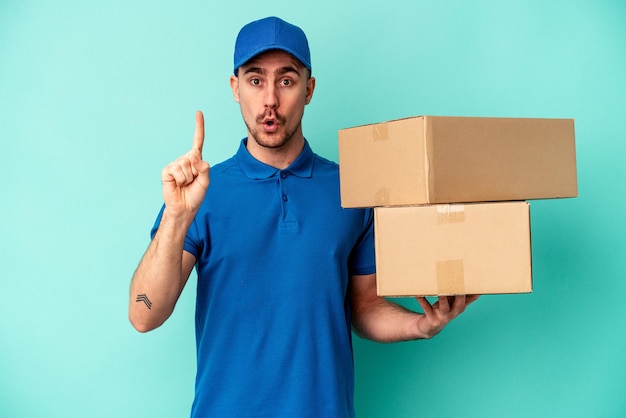 Young delivery caucasian man isolated on blue background having some great idea, concept of creativity.