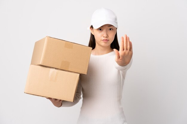 Young delivery Chinese woman over isolated white background making stop gesture with her hand