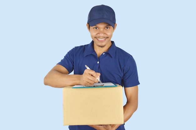 young delivery holding box and writing something on clipboard.