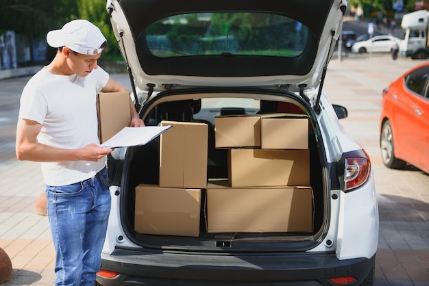 車のクリップボードの若い配達人チェックリスト