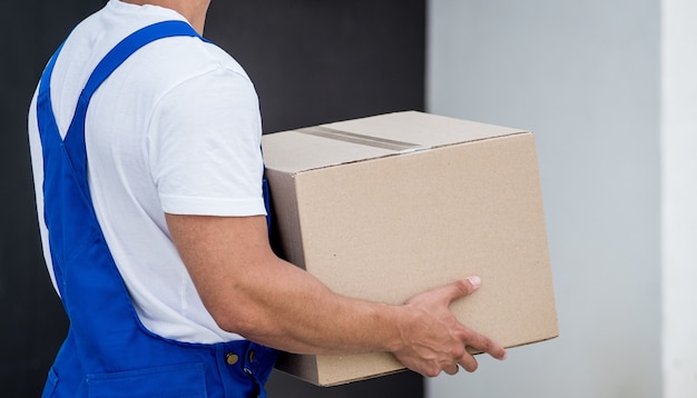 Young delivery man hold a cardboard box in his hands