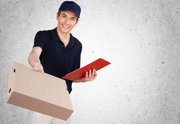 Молодой доставщик держит коробку и улыбается