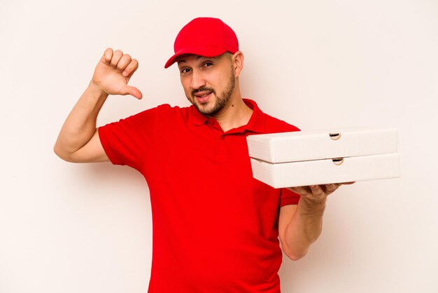 Young delivery man holding pizzas isolated on beige background feels proud and self confident example to follow