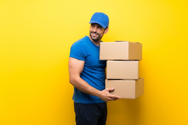 Young delivery man over isolated yellow wall