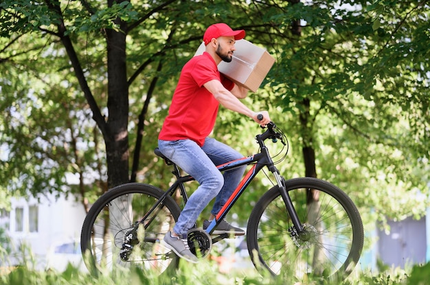 Young delivery man riding bicycle with parcel