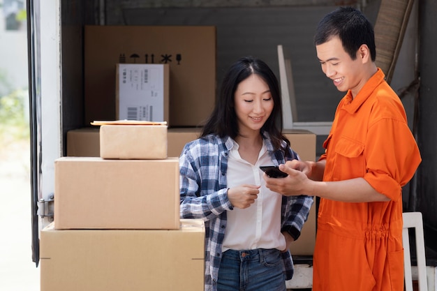 Photo young delivery man showing information about parcels to woman