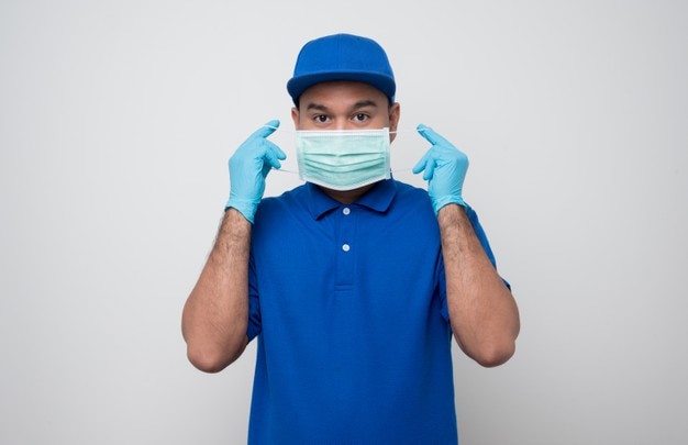 Young delivery man with a mask in a blue uniform