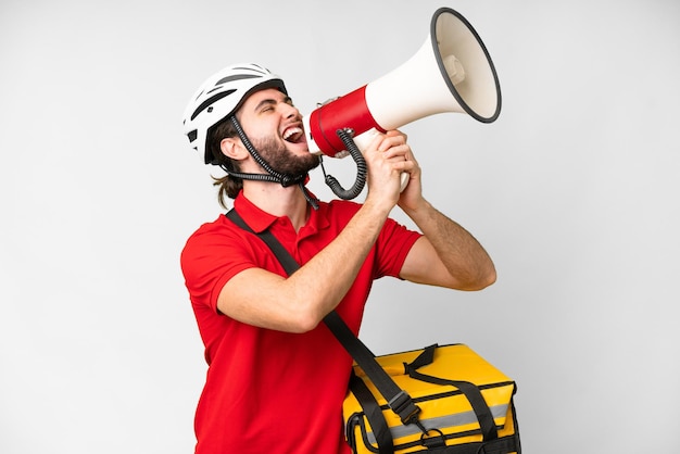 Young delivery man with thermal backpack over isolated white background shouting through a megaphone