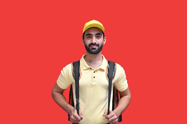 Young delivery man in yellow t shirt carrying backpack with takeaway food indian pakistani model