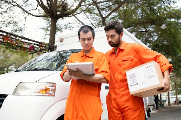 Photo young delivery men checking information for delivery near car