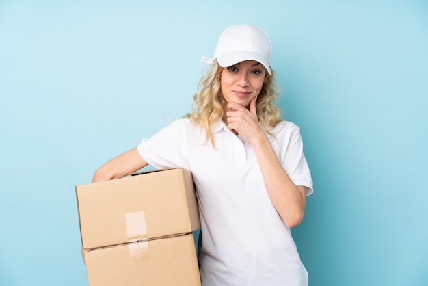 Young delivery woman on blue laughing